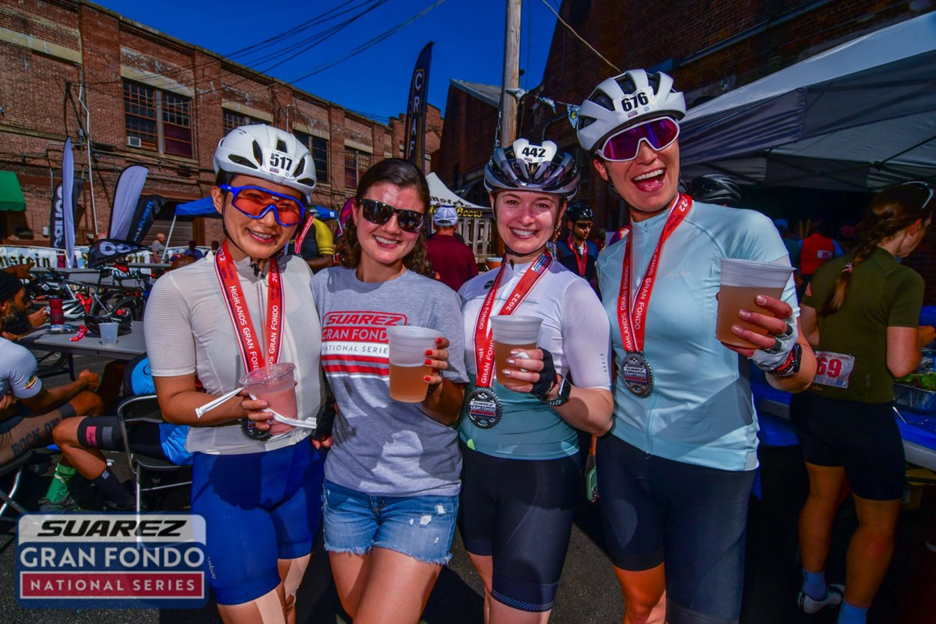 Women Drinking beer after finishing a cycling race standing with their medals